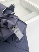 Giacca blu elegante con etichetta cura, ambiente minimalista e sobrio, stile raffinato e pratico.