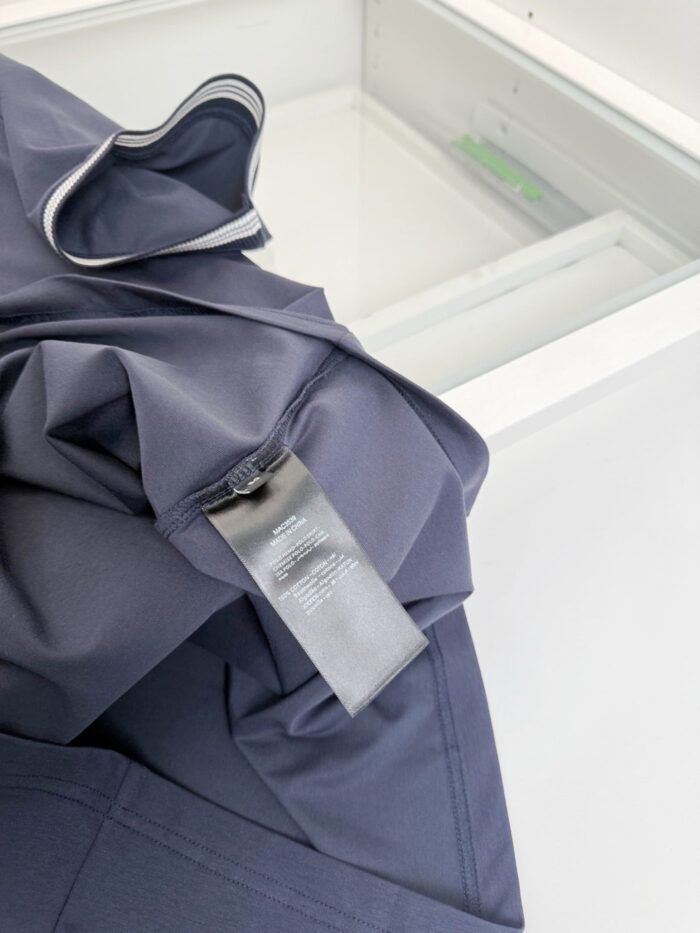 Giacca blu elegante con etichetta cura, ambiente minimalista e sobrio, stile raffinato e pratico.