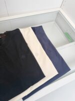 Set di magliette casual in navy, bianco e azzurro su sfondo minimalista.