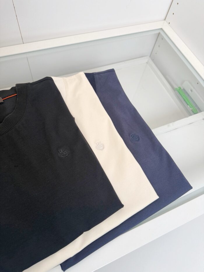 Set di magliette casual in navy, bianco e azzurro su sfondo minimalista.