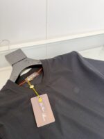 Maglietta nera semplice con dettaglio arancione e etichetta colorata, stile elegante e versatile.