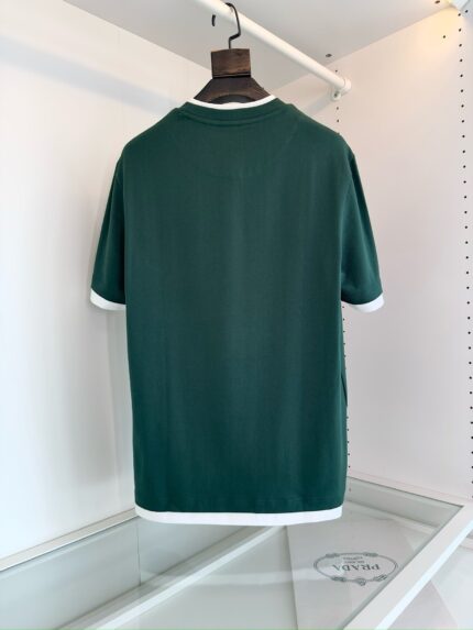 Camicia verde con bordo bianco, maniche corte, stile sportivo e raffinato, display elegante su appendiabiti.