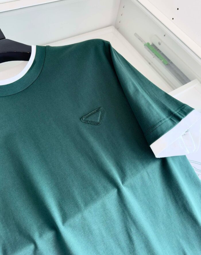 T-shirt verde con bordo bianco e logo triangolare tono su tono, stile casual e moderno.