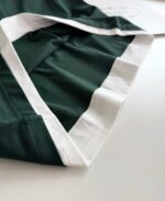Tessuto verde sportivo con bordo bianco, ideale abbigliamento casual e attivo elegante.