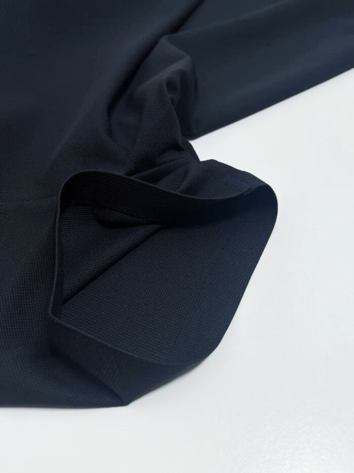 Tessuto blu navy elegante, morbido, con finitura lucida e pieghe delicate su sfondo bianco.
