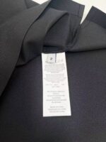 Giacca nera elegante con etichetta bianca, stile raffinato e dettagli di alta qualità.