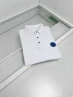 Maglietta polo bianca con patch blu, display elegante, stile casual raffinato.