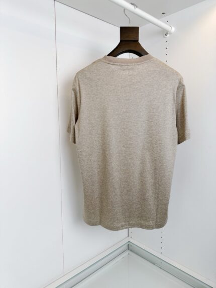 Maglietta beige casual su appendiabiti, stile minimalista e semplice da indossare.