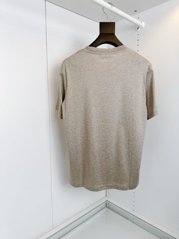 Maglietta beige casual su appendiabiti, stile minimalista e semplice da indossare.