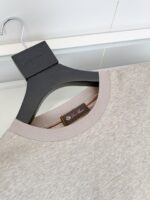 Maglia casual grigia con collo a coste, curva moderna e dettagli eleganti su supporto nero.