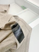 Maglietta beige morbida con etichetta nera, casual e confortevole, ideale per look quotidiani.
