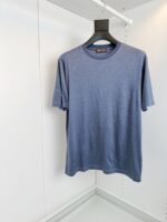 Maglietta blu semplice e versatile su appendiabiti nero, ideale per look casual e quotidiani.