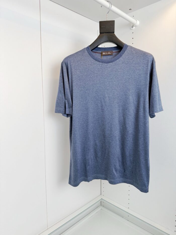 Maglietta blu semplice e versatile su appendiabiti nero, ideale per look casual e quotidiani.