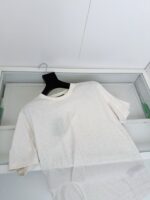 Maglietta bianca casual su appendiabiti in ambiente minimalista e luminoso.