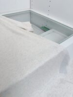Tessuto morbido su mobile in ambiente minimalista e luminoso con box in vetro trasparente.