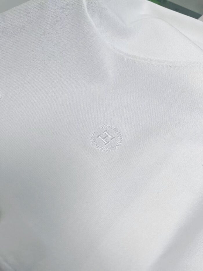 Maglietta bianca minimalista con logo discreto, tessuto morbido e design elegante.