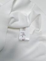 Etichetta di cura su camicia bianca leggera e morbida, istruzioni per lavaggio e materiali.