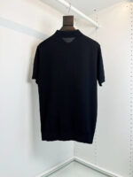 Maglietta polo nera elegante in cotone, vista posteriore su appendiabiti bianco.