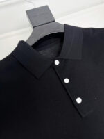 Maglietta polo nera elegante su gancio in legno, stile classico e di alta qualità.