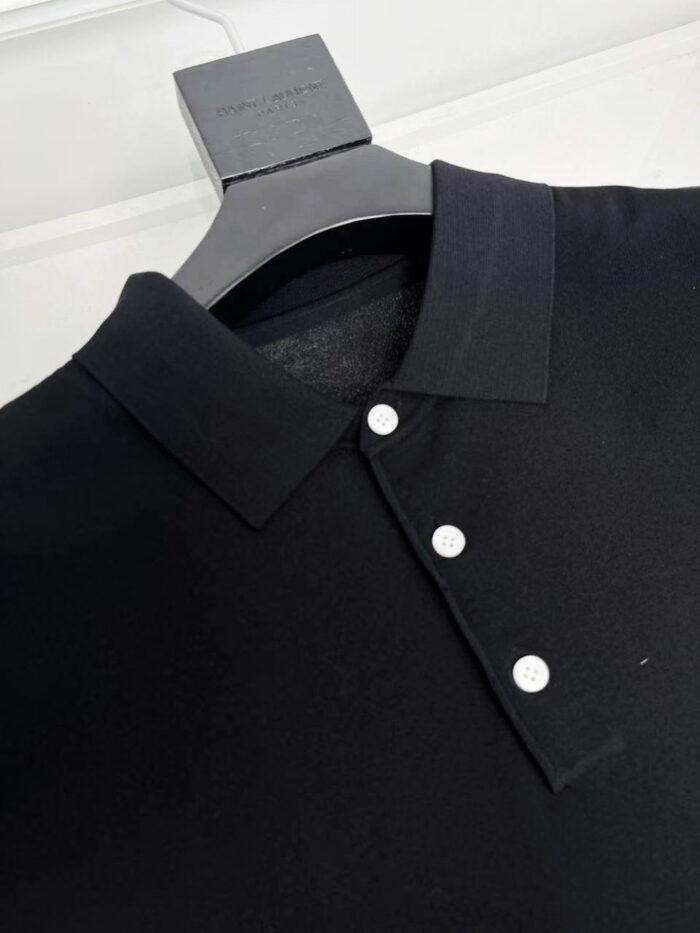 Maglietta polo nera elegante su gancio in legno, stile classico e di alta qualità.