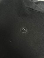Dettaglio elegante di abbigliamento nero con logo minimalista in tessuto di alta qualità.