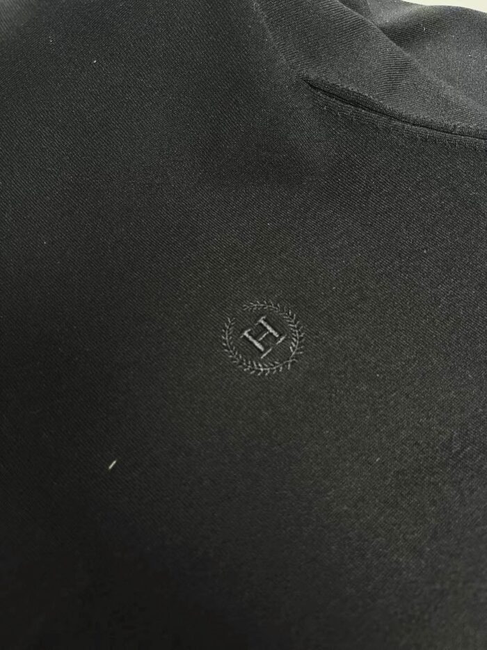 Dettaglio elegante di abbigliamento nero con logo minimalista in tessuto di alta qualità.
