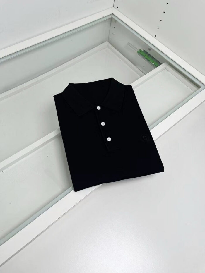 Maglietta polo nera elegante su superficie di vetro, stile minimalista e di alta qualità.