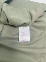 Etichetta garmentale su tessuto verde chiaro, con istruzioni di cura e tag taglia L.