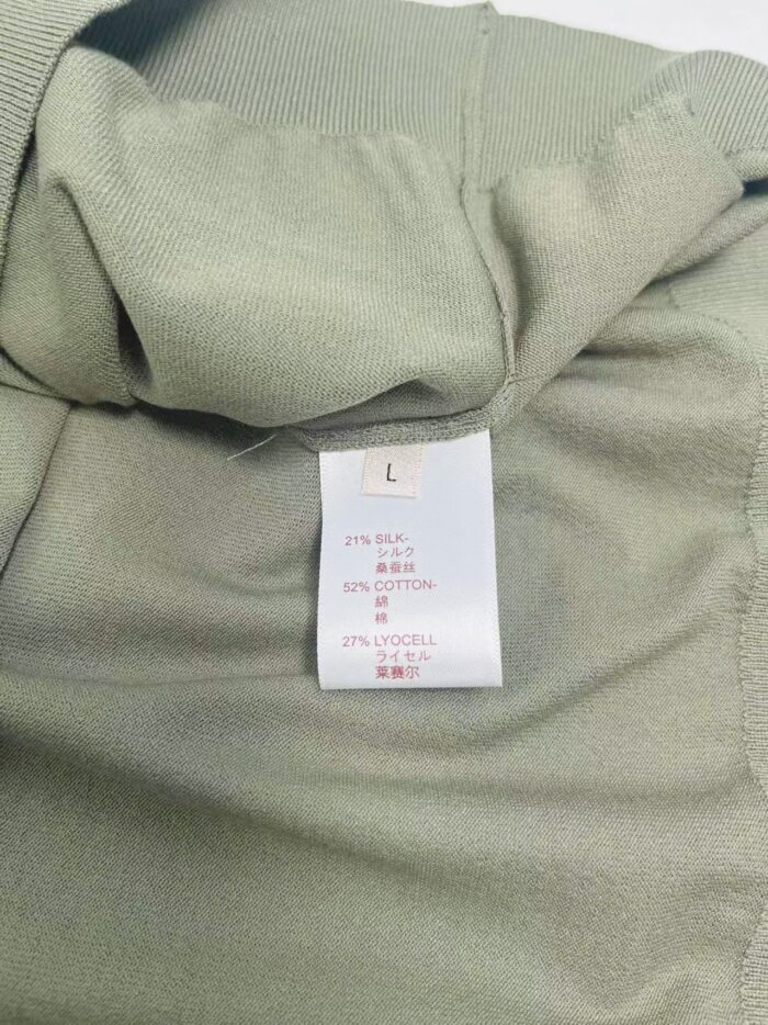 Etichetta garmentale su tessuto verde chiaro, con istruzioni di cura e tag taglia L.