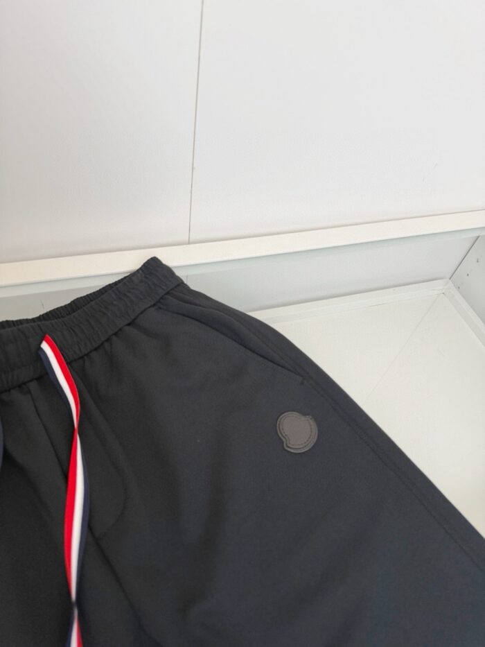 Pantaloncini sportivi neri con drawstring colorata e logo discreto, stile casual e moderno.