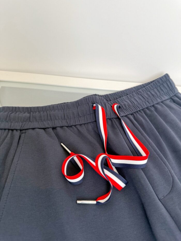 Pantaloni jogger grigi con stringhe colorate e aglet metallico, comfort e stile casual.
