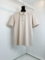Maglietta polo beige classica su appendiabiti minimalista, versatile e elegante per ogni occasione.