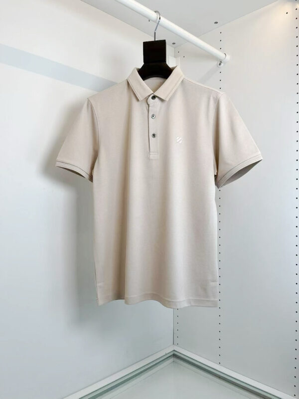 Maglietta polo beige classica su appendiabiti minimalista, versatile e elegante per ogni occasione.