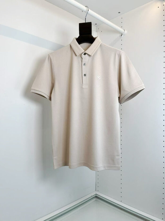 Maglietta polo beige classica su appendiabiti minimalista, versatile e elegante per ogni occasione.