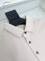 Camicia beige elegante con colletto classico, bottoni scuri e stile minimalista moderna.