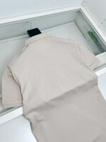 Maglietta polo beige elegante in esposizione minimalista, perfetta per uno stile versatile e casual.