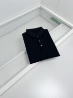 Camicia polo nera in esposizione minimalista, elegante e di qualità in vetrina moderna.