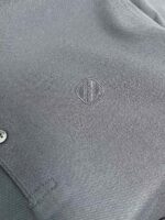 Maglietta casual in tessuto grigio con logo minimalista e dettaglio in metallo elegante.