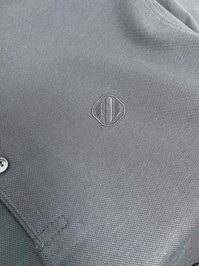 Maglietta casual in tessuto grigio con logo minimalista e dettaglio in metallo elegante.