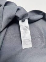 Etichetta di cura tessuto grigio, dettagli e simboli su abbigliamento elegante.