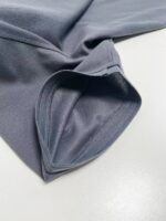 Manica di abbigliamento sportivo grigia, tessuto leggero e cuciture precise, stile e funzionalità.
