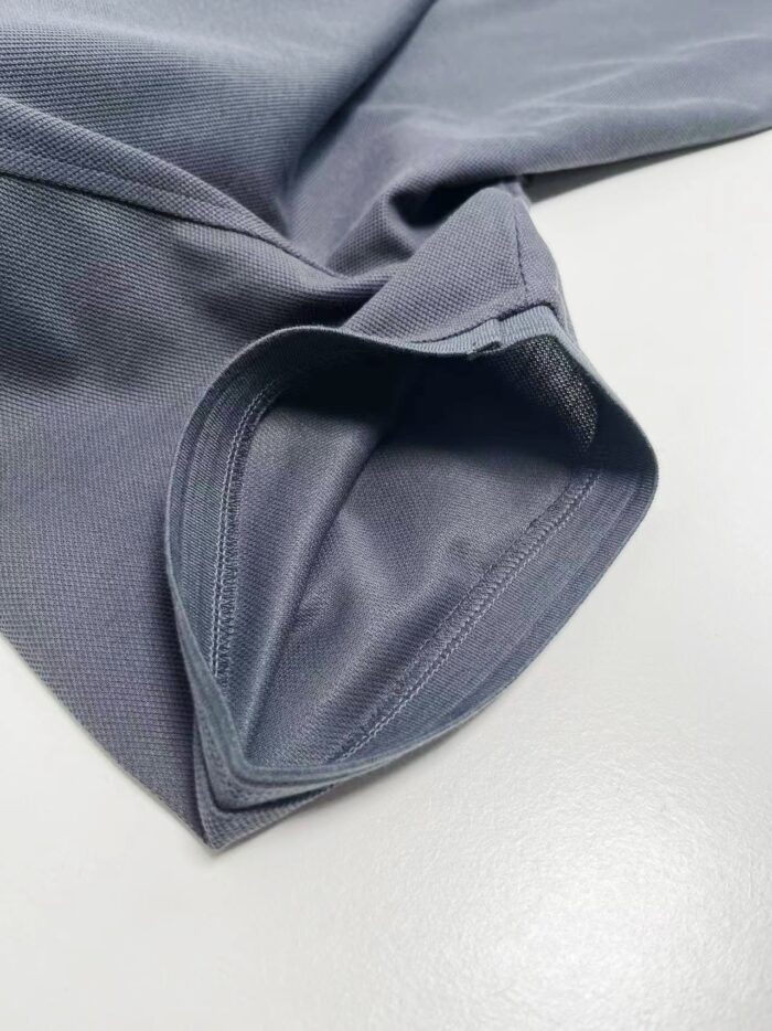 Manica di abbigliamento sportivo grigia, tessuto leggero e cuciture precise, stile e funzionalità.