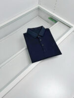 Maglietta polo navy elegante in esposizione su superficie moderna, ideale per look casual sofisticati.