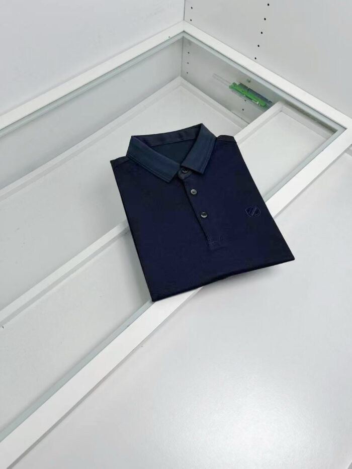 Maglietta polo navy elegante in esposizione su superficie moderna, ideale per look casual sofisticati.