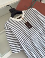 Maglietta a righe navy e bianco con borsa in pelle marrone e dettagli trendy.
