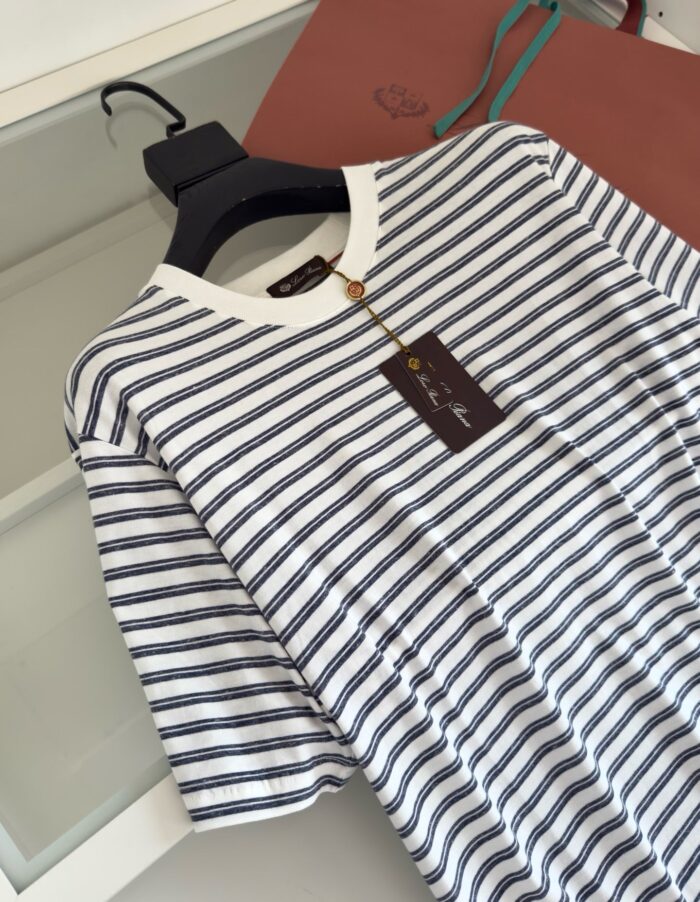 Maglietta a righe navy e bianco con borsa in pelle marrone e dettagli trendy.