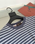 Camicia a righe navy e bianco, stile casual, con dettagli colorati su sfondo neutro.