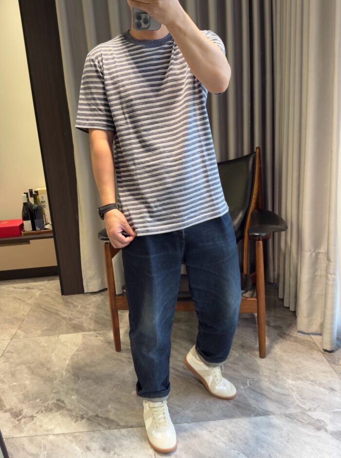 Selfie di stile casual con jeans, sneakers chiari e accessori minimalisti in ambiente moderno.