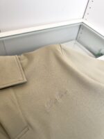 Camicia polo beige elegante con ricamo sottile, presenta dettagli di alta qualità in negozio raffinato.