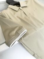Maglietta polo beige con dettagli bianchi, stile casual elegante e tessuto morbido.